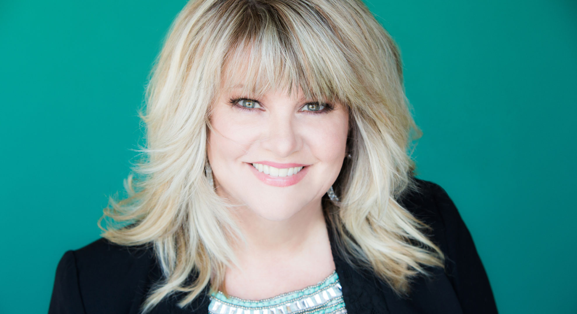 A woman with blonde hair and bangs smiles for the camera.