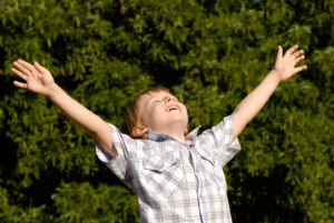 A young boy with his arms raised in the air.